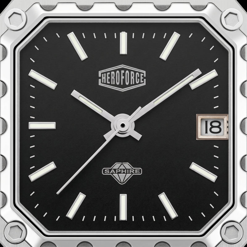 Close-up of a square analog watch face with a black dial, silver-tone hands and markers, a date window showing 18, and visible HEROFORCE and SAPWIRE branding.