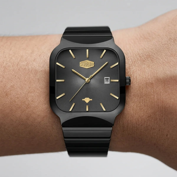 A black rectangular analog watch with gold-tone hands, hour markers, and logo details, shown worn on a person's wrist against a light gray background.