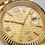 A close-up of a gold-tone wristwatch with a textured dial, fluted bezel, and matching metal link bracelet on a white background.