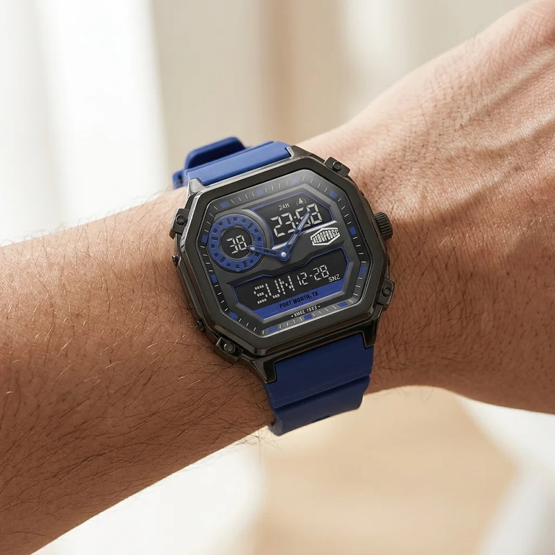 A close-up of a rugged digital watch with a blue strap and black case, worn on a person's wrist against a softly blurred light background.
