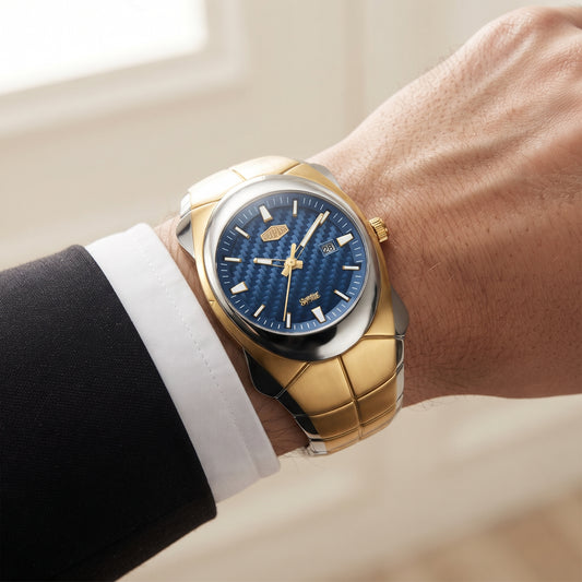A close-up of a wrist wearing a two-tone gold and stainless steel watch with a textured blue dial, styled with a white dress shirt cuff and black suit jacket.