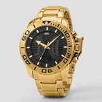 A gold-tone stainless steel watch with a black dial featuring a grid pattern, a rotating bezel with white numerals, and a matching gold-tone link bracelet, shown against a light gray background.