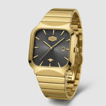 A gold-tone stainless steel watch with a rectangular, rounded black square dial and a matching gold-tone metal link bracelet, shown on a light gray background.