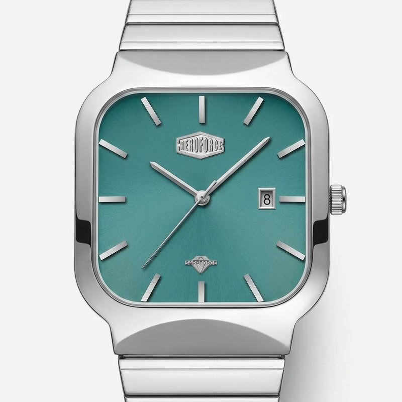 A silver-tone stainless steel wristwatch with a square bezel and a metallic teal-green dial, featuring silver stick indices, silver hands, a date window at 3 o'clock, and a matching metal link bracelet.