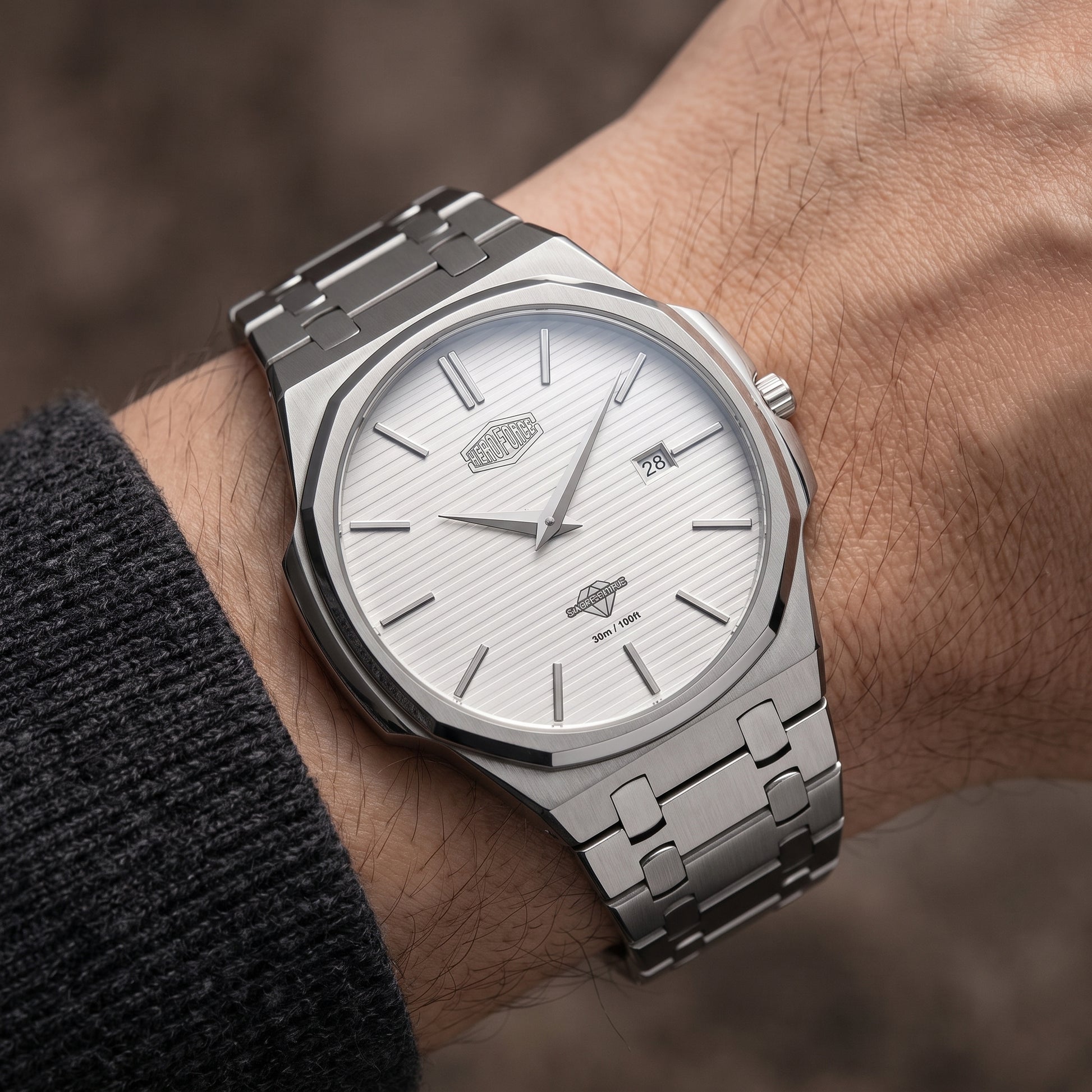 A silver stainless steel wristwatch with a textured white dial and matching metal link bracelet, shown worn on a person's wrist.