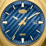 Close-up of a gold-tone wristwatch dial with a textured blue patterned face, gold hour markers and hands, and a date window showing 28.