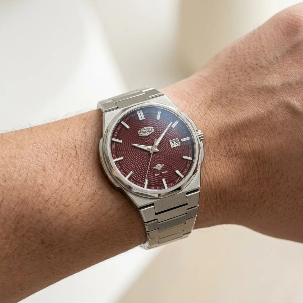 A wristwatch with a silver stainless steel bracelet and case, featuring a textured dark red dial, shown worn on a person's wrist.