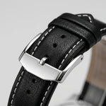 Close-up of a black textured leather watch strap with white contrast stitching and a polished silver-tone metal buckle.