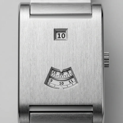 Close-up of a brushed stainless steel watch face with a small square day window showing 10 and a fan-shaped hour-index window below, on a light gray background.