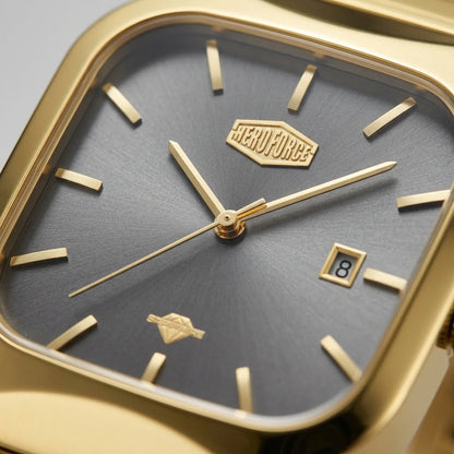 Close-up of a gold-tone wristwatch with a dark gray textured dial, gold baton hour markers, gold hands, and a date window at 3 o'clock. The brand name 'HERO FORCE' is visible on the dial.