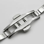Close-up of a polished stainless steel watch band clasp and adjacent links on a light gray background.