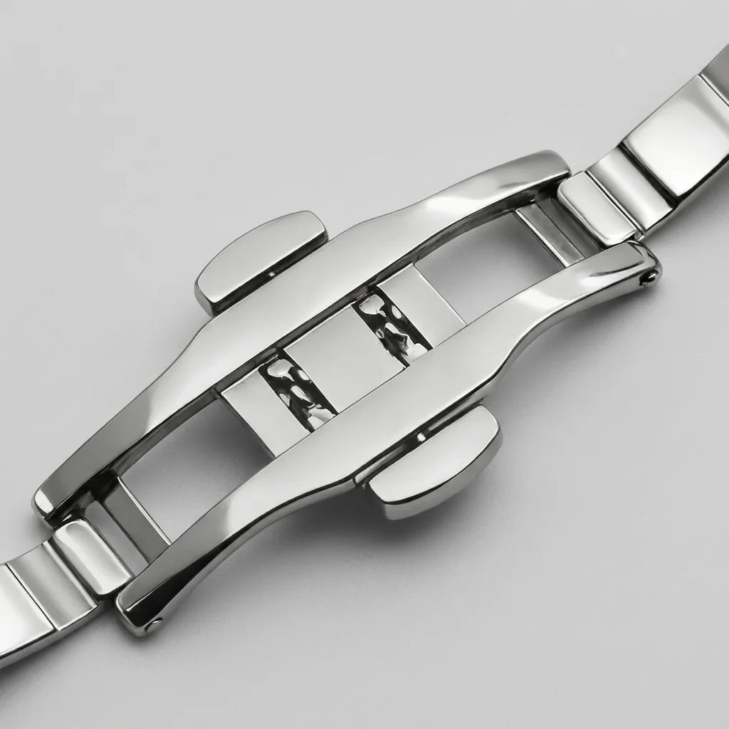Close-up of a polished stainless steel watch band clasp on a light gray background.