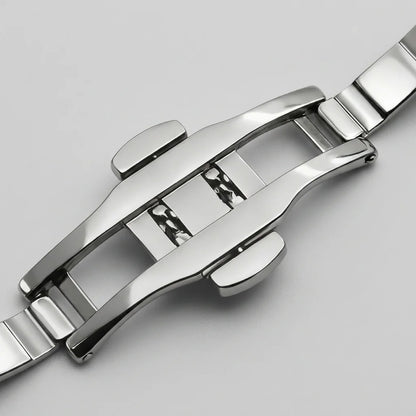 Close-up of a polished stainless steel watch band clasp on a light gray background.