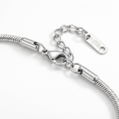Close-up of a silver-toned snake chain bracelet showing the lobster clasp, extension chain, and a polished tag engraved with 'SS STEEL' .