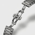 Close-up of a stainless steel link watch band with a polished folding clasp on a light gray background.