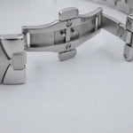 Close-up of a stainless steel watch band clasp on a light gray background.
