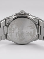Close-up rear view of a stainless steel wristwatch with a metal link bracelet, showing the brushed case back engraved with a mountain design