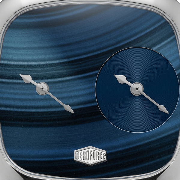 Close-up of a watch dial with a blue marbled or swirled face, silver sword-shaped hands, a smaller matching blue circular subdial, and a visible HEROFORCE logo at the bottom.