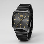 A HEROFORCE wristwatch with a matte black ceramic case and integrated link bracelet, featuring a black dial with gold-tone indices and hands, and a date window at 3 o'clock.