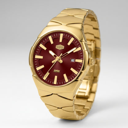 A gold-tone stainless steel watch with a deep burgundy red dial, featuring gold-tone hour markers, hands, and a date window at the 3 o'clock position.