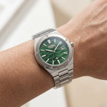 Stainless steel wristwatch with a green wave patterned on a hand
