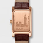 The back of a rectangular rose gold watch with a brown leather strap
