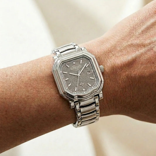 Watch on wrist - Silver wristwatch with octagonal rectangular case, metallic bracelet, gray textured dial, silver markers, and date window