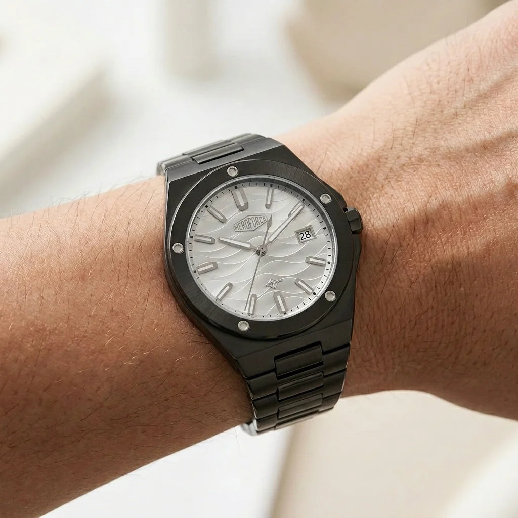 Worn on wrist of A men's analog watch with a black metal case and link bracelet, featuring a silver dial with a wavy pattern, silver hour markers