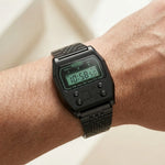 Wrist worn of Black metallic digital wristwatch with rectangular face and green backlit display