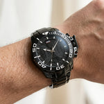 Wrist worn of Black stainless steel watch with black geometric dial, oversized bezel, and metal bracelet