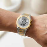 Wrist worn of Round digital wristwatch with alternating silver and gold segmented band, gold bezel, and three gold side buttons