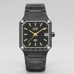 A rugged black watch with a textured octagonal case, black dial, gold-tone hands and indices, and a black segmented strap