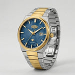 A two-tone stainless steel and gold wristwatch with a textured blue dial, featuring a date window and a clean studio background.