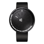 A minimalist black analog watch with a matte black strap, a black round case, and a black dial featuring white markings and hands, centered on a solid black background.