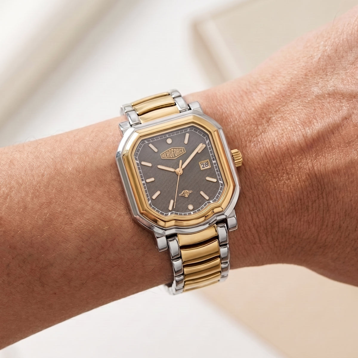A two-tone wristwatch with a gold and silver link bracelet and a dark gray dial, shown worn on a person's wrist.