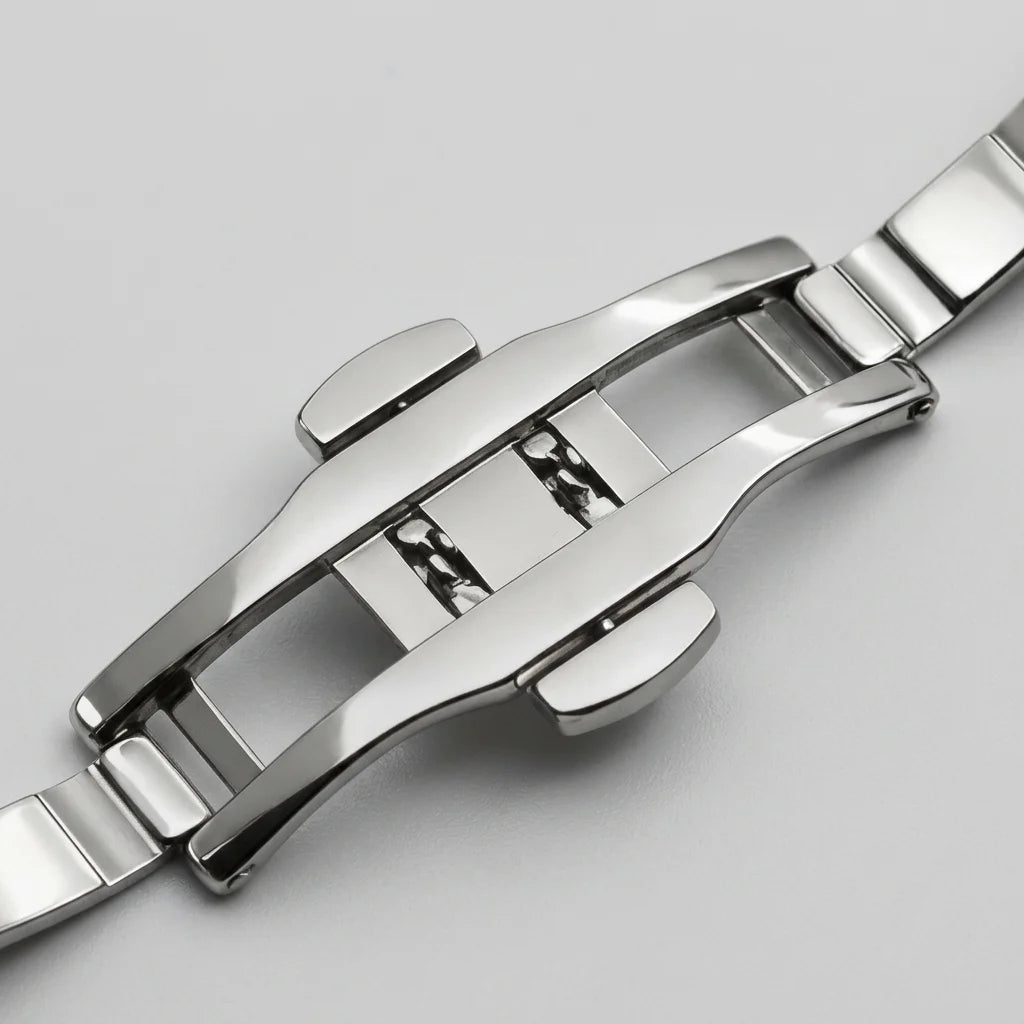 Close-up of a polished stainless steel watch band clasp on a light gray background.
